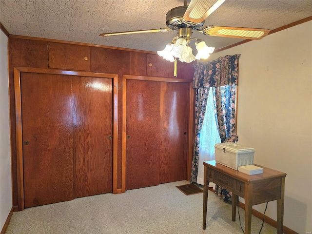 interior space featuring ceiling fan, crown molding, and wood walls