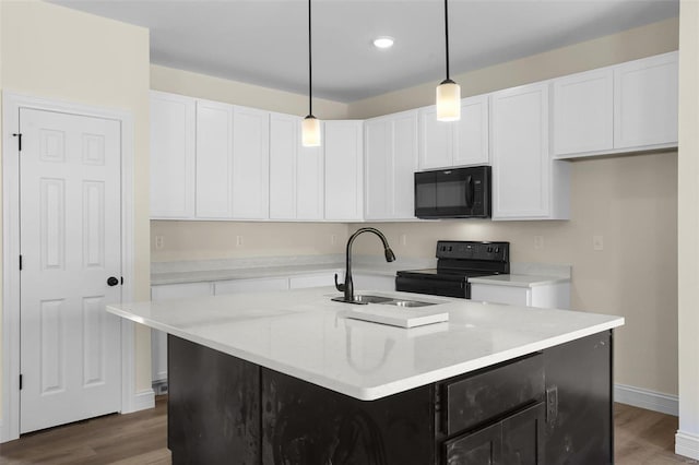 kitchen with hanging light fixtures, a kitchen island with sink, and black appliances