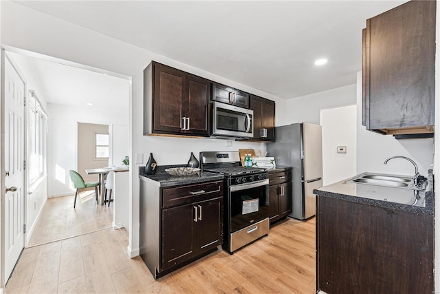 kitchen with sink, light wood-type flooring, dark brown cabinets, and appliances with stainless steel finishes