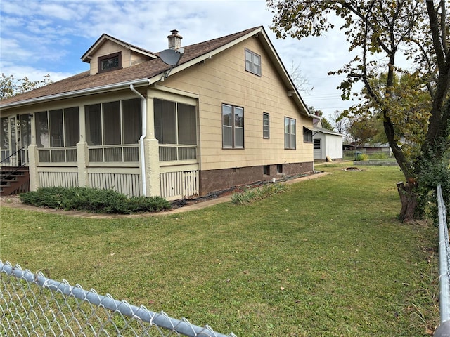 view of home's exterior with a sunroom and a lawn