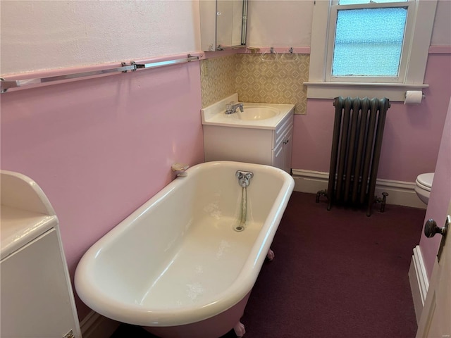 bathroom with vanity, toilet, radiator heating unit, and a bath