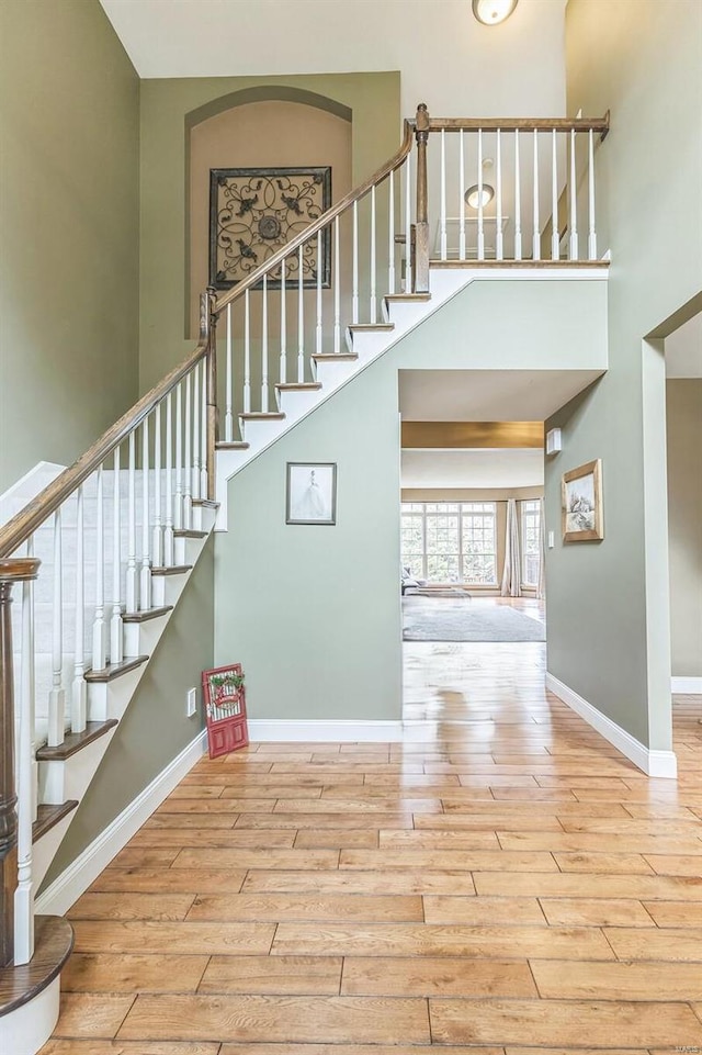 staircase with wood-type flooring and a towering ceiling