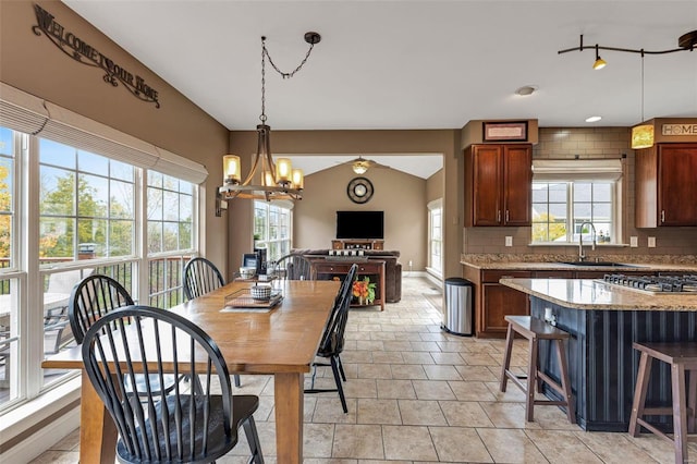 dining space featuring ceiling fan with notable chandelier, sink, and vaulted ceiling