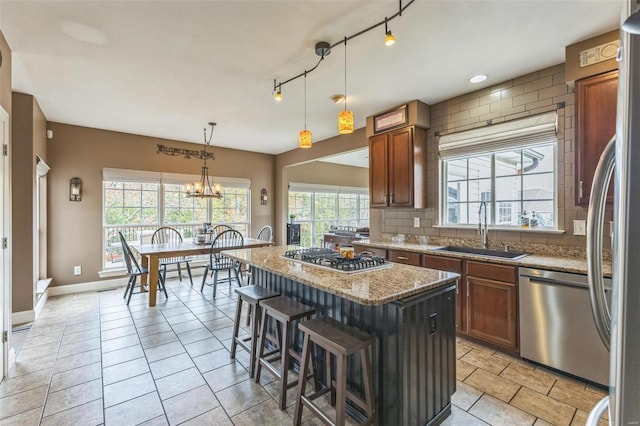 kitchen featuring a center island, sink, hanging light fixtures, stainless steel appliances, and tasteful backsplash