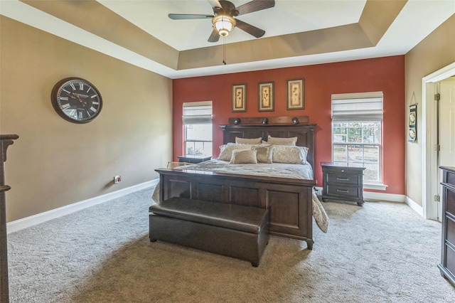 carpeted bedroom with a tray ceiling and ceiling fan