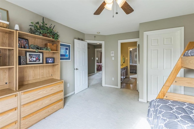 bedroom featuring ceiling fan, light colored carpet, and connected bathroom