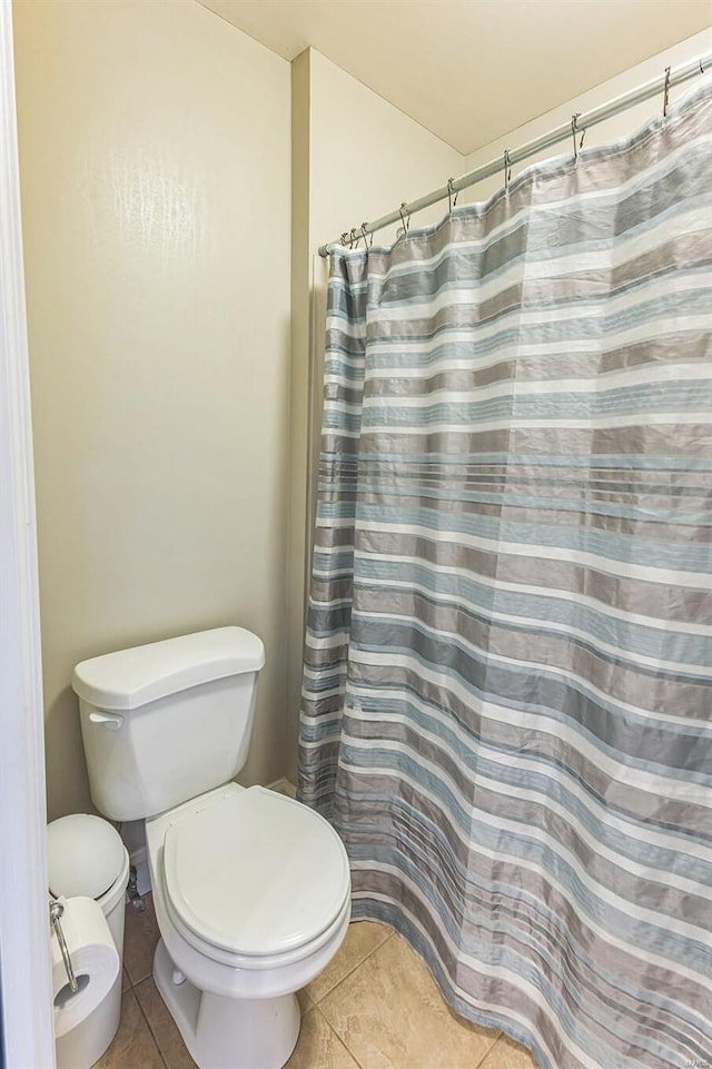 bathroom featuring toilet, tile patterned flooring, and walk in shower