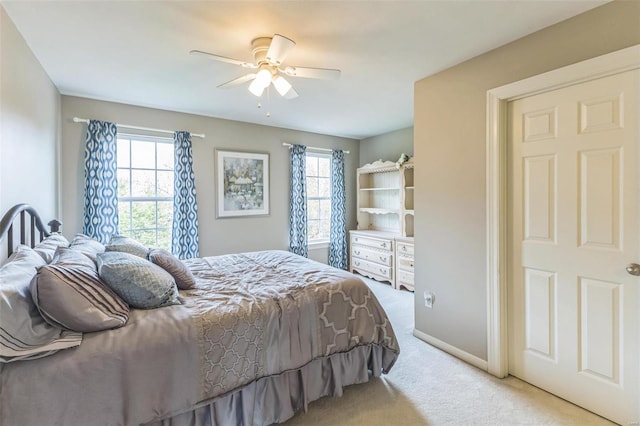 bedroom featuring multiple windows, ceiling fan, and light carpet