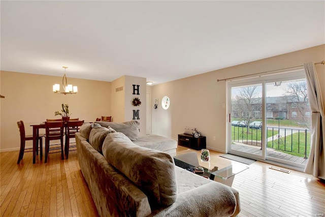 living room with light wood-type flooring and an inviting chandelier