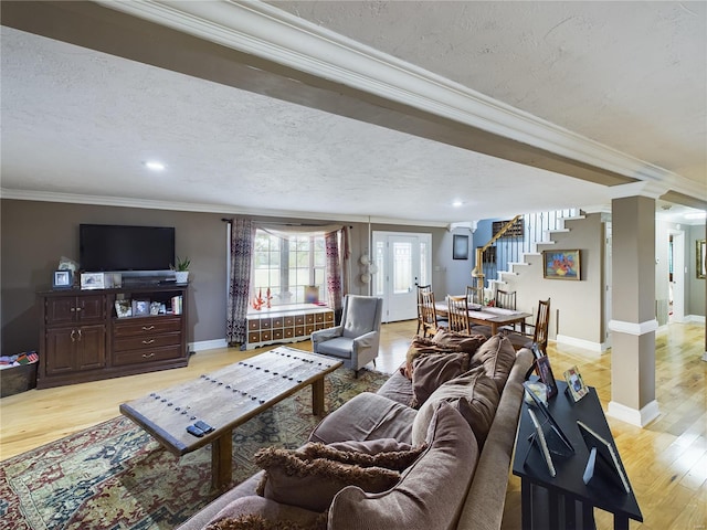 living room with ornamental molding, a textured ceiling, and light wood-type flooring