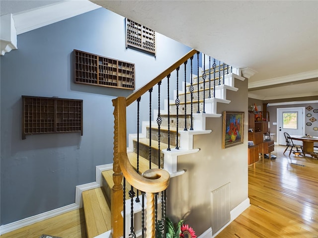 staircase featuring wood-type flooring and ornamental molding