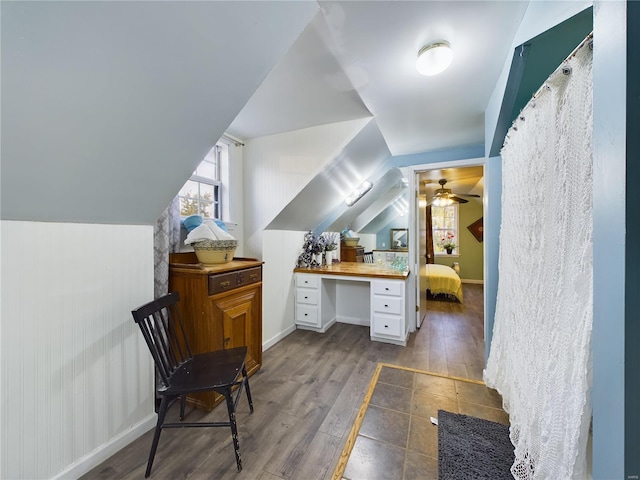 bonus room with ceiling fan, built in desk, dark wood-type flooring, and lofted ceiling