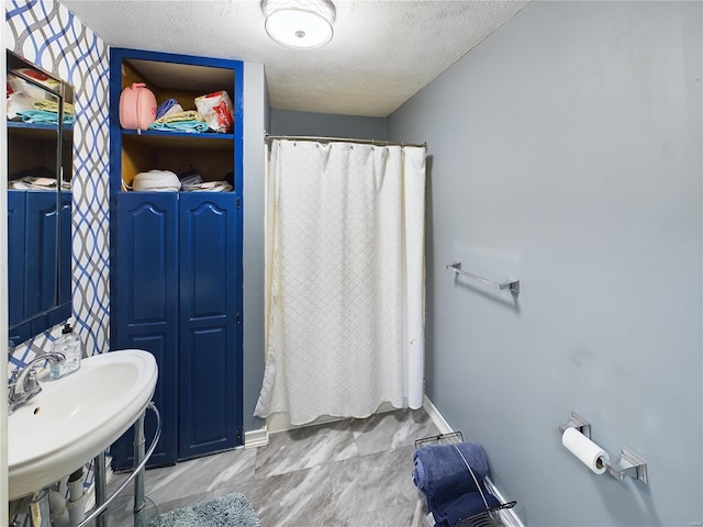 bathroom with a shower with curtain, sink, and a textured ceiling