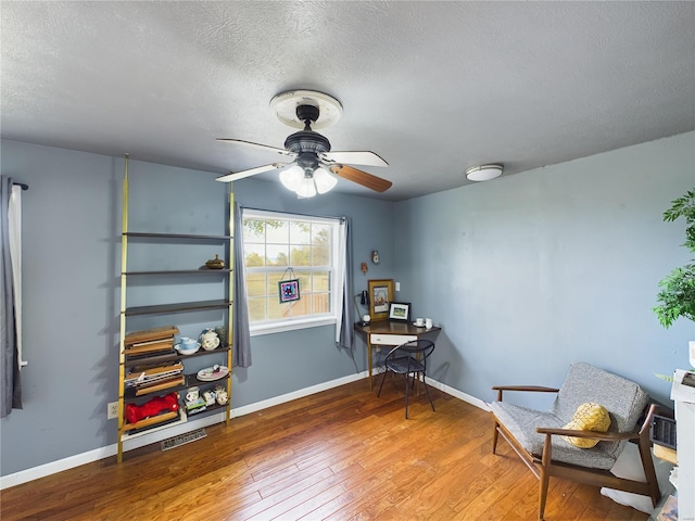 sitting room with ceiling fan, wood-type flooring, and a textured ceiling