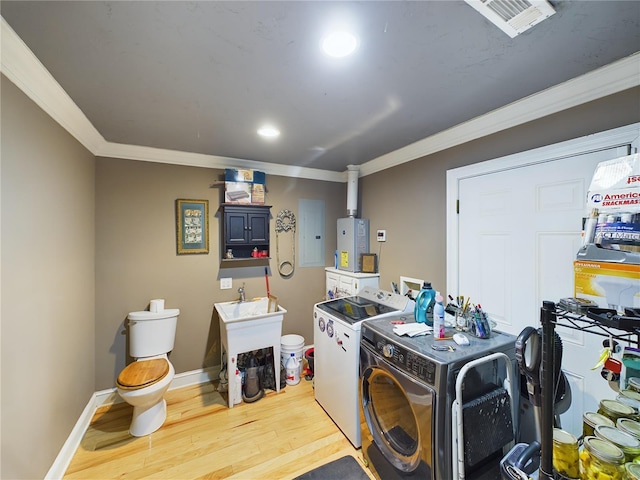 clothes washing area with independent washer and dryer, electric panel, light hardwood / wood-style floors, and crown molding