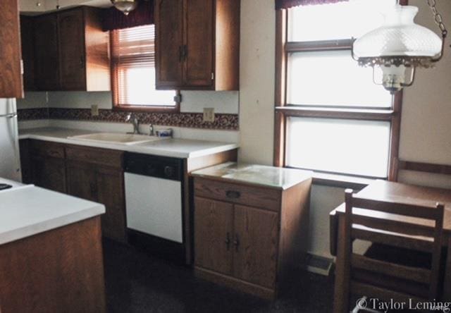 kitchen with white dishwasher, sink, stainless steel refrigerator, and a healthy amount of sunlight