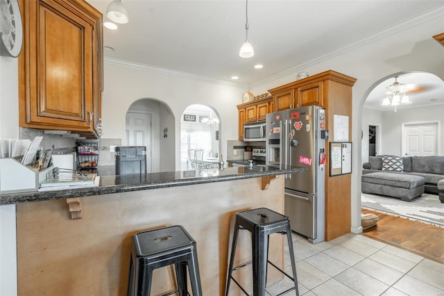 kitchen with kitchen peninsula, appliances with stainless steel finishes, a breakfast bar, and light hardwood / wood-style flooring