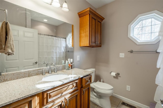 bathroom with a wealth of natural light, tile patterned flooring, vanity, and toilet