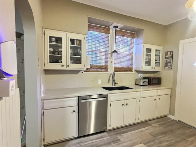 kitchen featuring radiator, white cabinetry, sink, stainless steel dishwasher, and light wood-type flooring