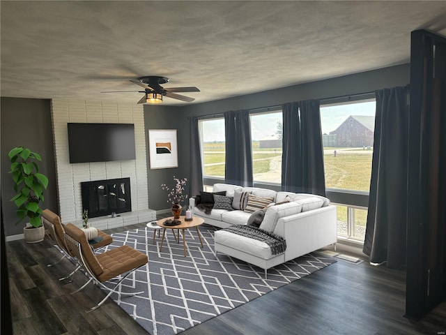 living room with a healthy amount of sunlight, a fireplace, and dark hardwood / wood-style floors