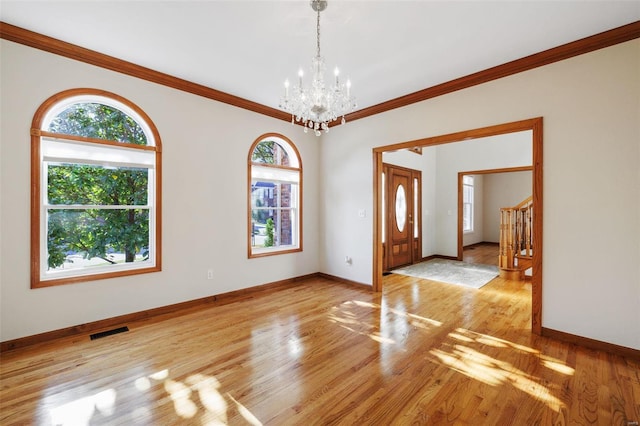 unfurnished room featuring a chandelier, ornamental molding, and light hardwood / wood-style flooring