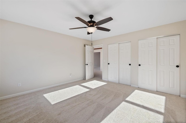 unfurnished bedroom with ceiling fan, carpet floors, and two closets