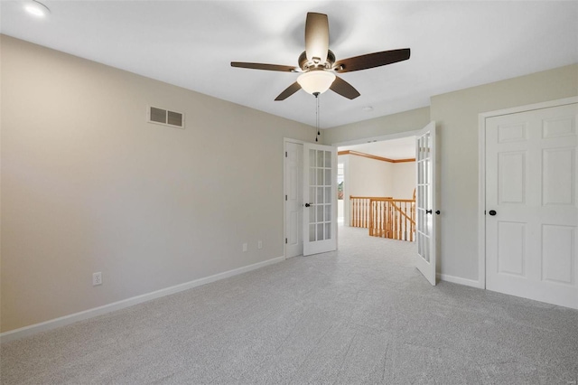 unfurnished room with ceiling fan, light colored carpet, and french doors