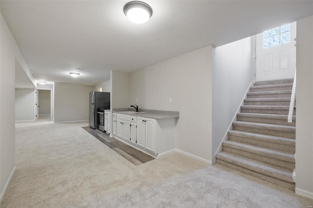 interior space with sink, light carpet, and stainless steel refrigerator