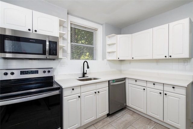 kitchen featuring decorative backsplash, stainless steel appliances, sink, white cabinets, and light tile patterned flooring