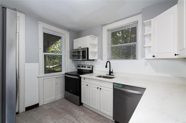 kitchen with backsplash, white cabinets, sink, light tile patterned flooring, and stainless steel appliances