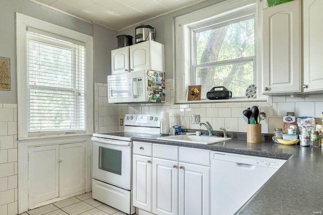 kitchen with white appliances, crown molding, sink, light tile patterned floors, and white cabinetry