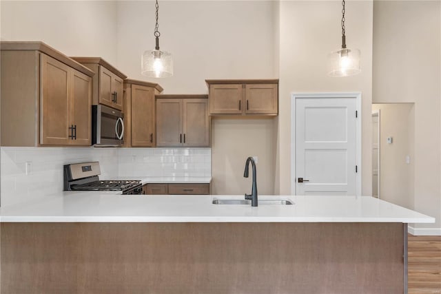 kitchen with sink, hanging light fixtures, appliances with stainless steel finishes, and tasteful backsplash