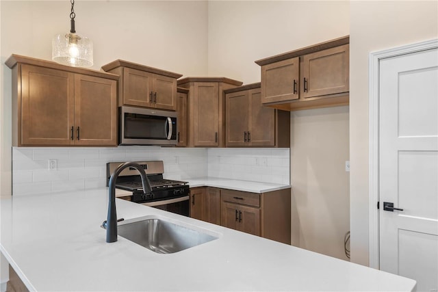 kitchen with sink, decorative backsplash, decorative light fixtures, kitchen peninsula, and stainless steel appliances