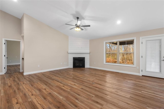 unfurnished living room featuring ceiling fan, a large fireplace, vaulted ceiling, and light wood-type flooring