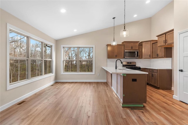 kitchen featuring pendant lighting, lofted ceiling, backsplash, appliances with stainless steel finishes, and kitchen peninsula