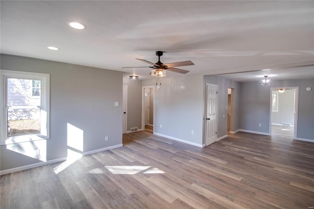 spare room featuring hardwood / wood-style floors and ceiling fan with notable chandelier