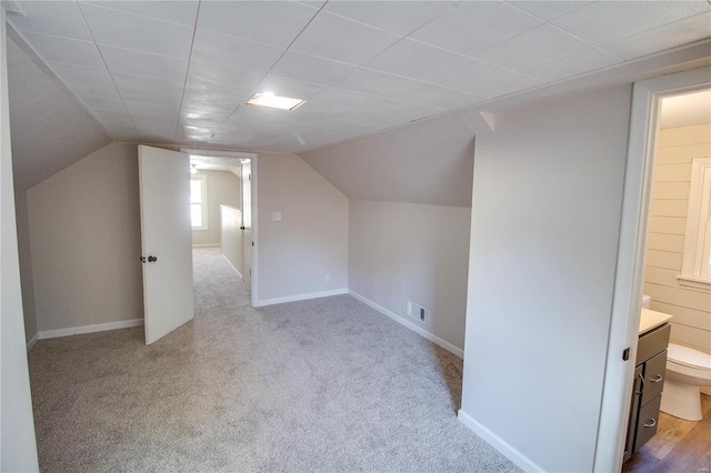 bonus room with light colored carpet and vaulted ceiling