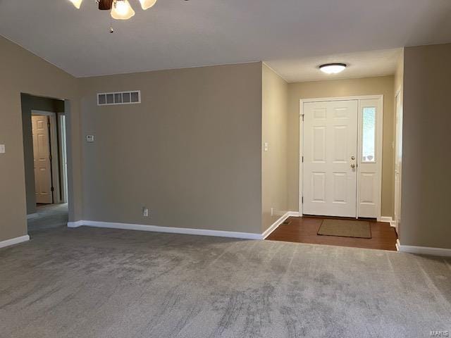 foyer featuring ceiling fan, vaulted ceiling, and dark carpet