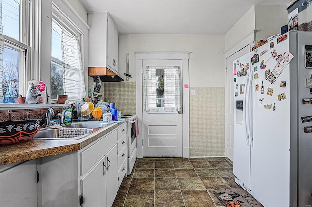 kitchen with white cabinets, plenty of natural light, sink, and white refrigerator with ice dispenser