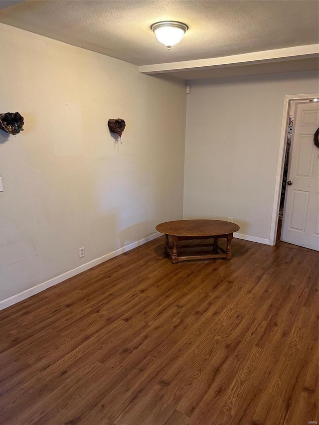 unfurnished room featuring a textured ceiling and dark hardwood / wood-style flooring