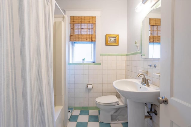 bathroom with a shower, toilet, and tile walls