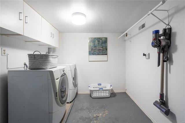 clothes washing area featuring washing machine and dryer and cabinets