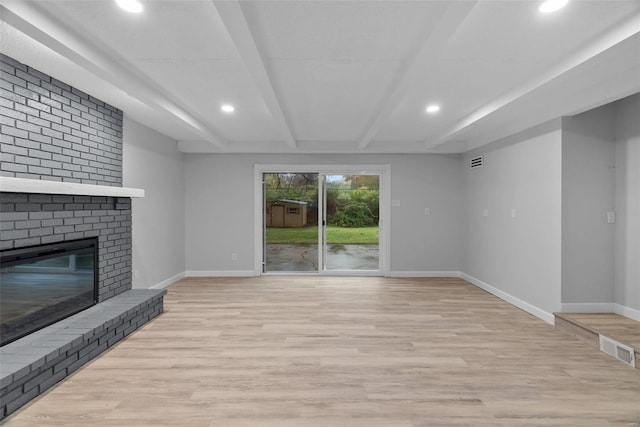 unfurnished living room with beam ceiling, a fireplace, and light hardwood / wood-style flooring