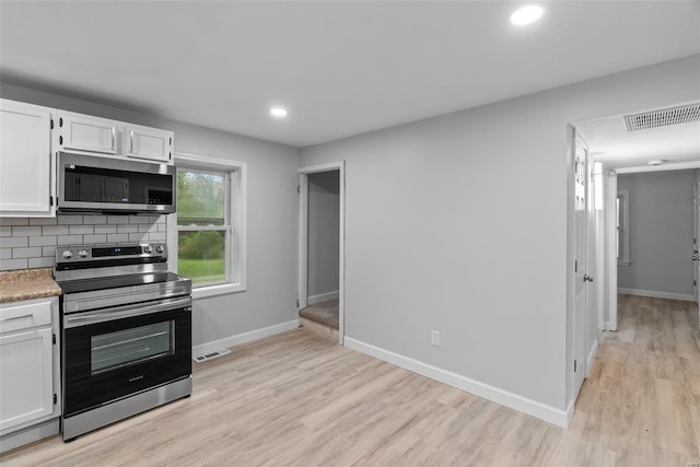 kitchen with decorative backsplash, white cabinetry, light hardwood / wood-style flooring, and appliances with stainless steel finishes