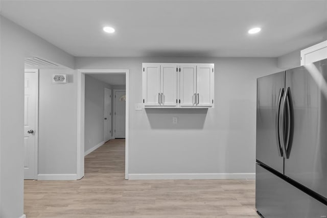 kitchen with white cabinets, stainless steel fridge, and light hardwood / wood-style floors