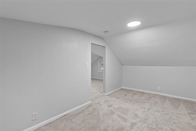 additional living space featuring light carpet and vaulted ceiling