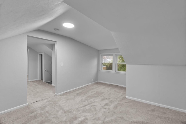 bonus room with light colored carpet and lofted ceiling