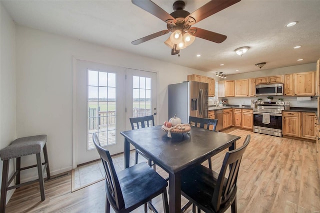 dining area with light wood-type flooring, a textured ceiling, and ceiling fan