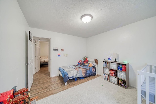 bedroom with a textured ceiling and light hardwood / wood-style floors