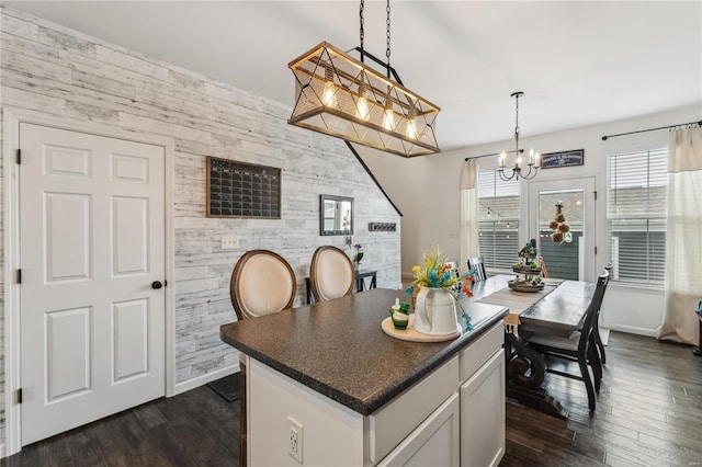 kitchen with dark countertops, wooden walls, decorative light fixtures, an inviting chandelier, and dark wood-style flooring